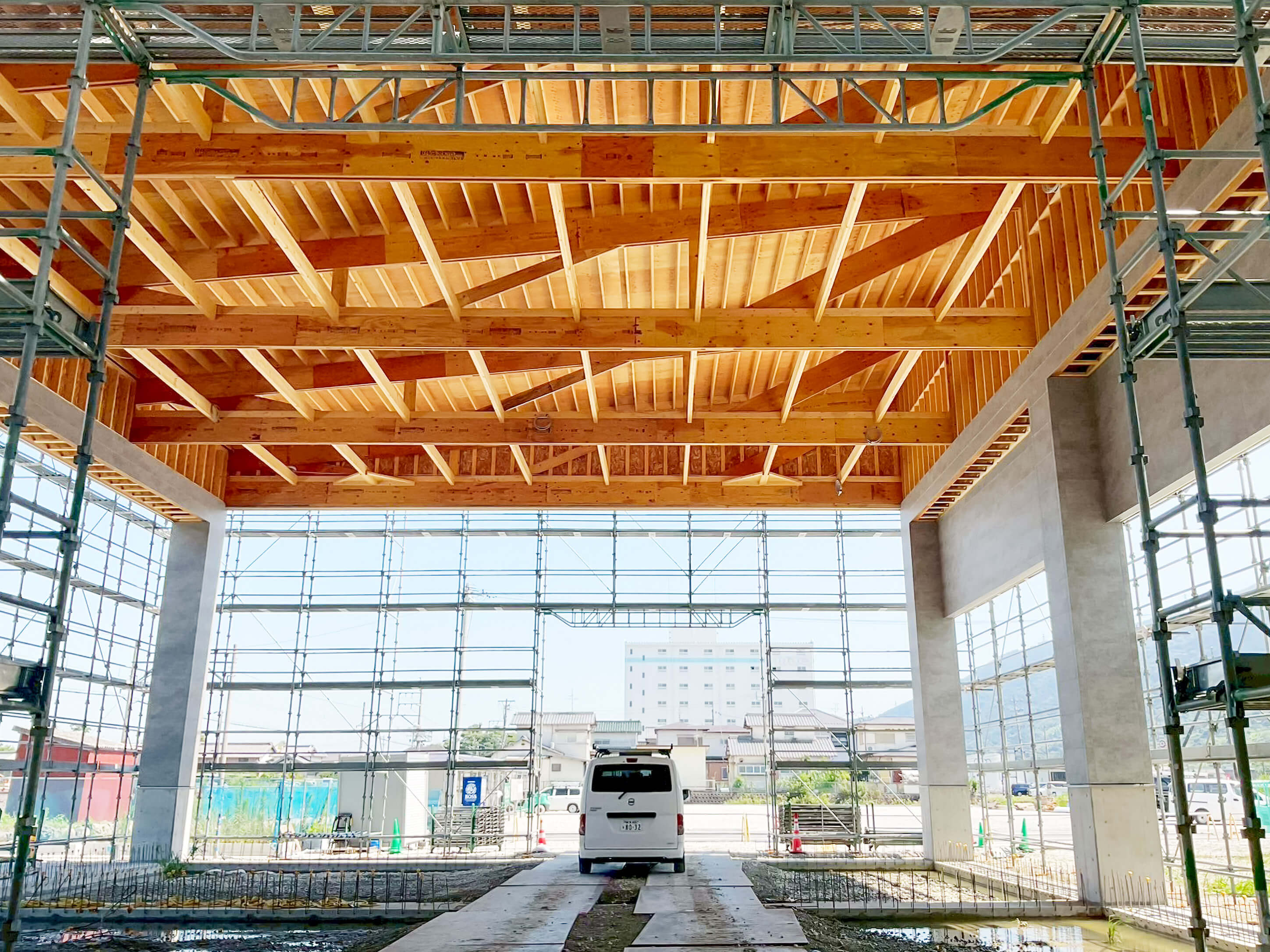 大開口の建屋で、木造梁と足場のある内部から外を見た風景