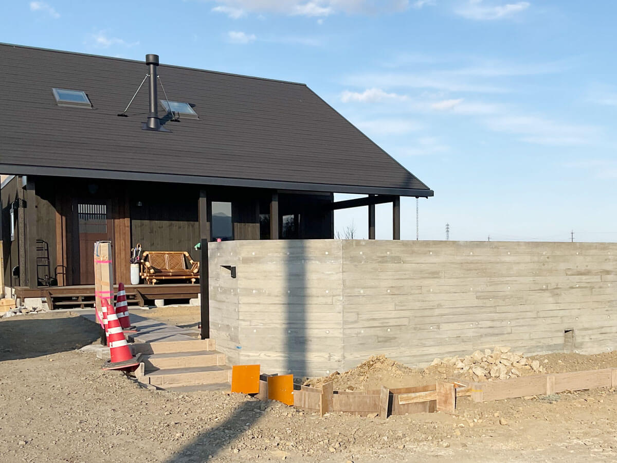 住宅外構の施工中で、打ち放しコンクリート擁壁と仮設養生がある現場